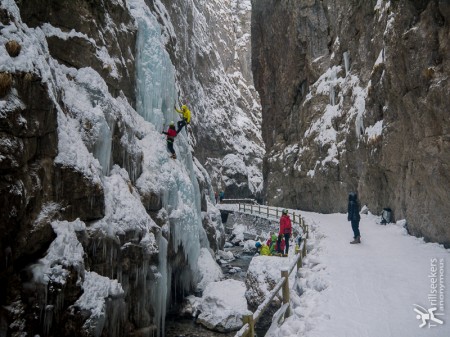 Ice climbing in Serrai di Sottoguda and tourist onlookers.